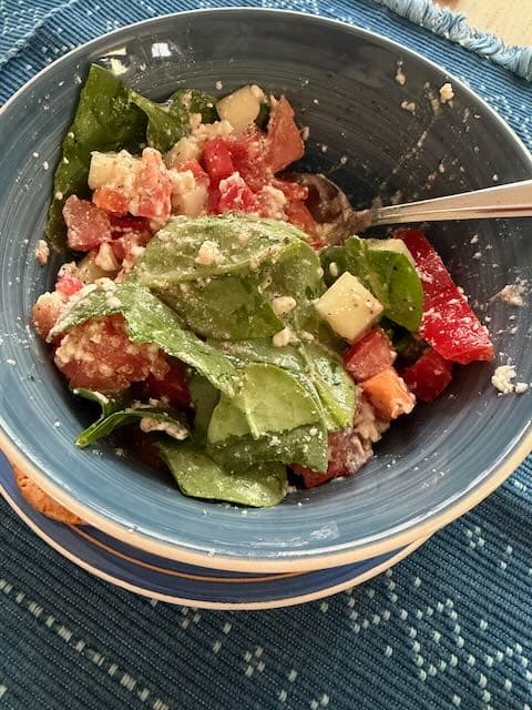 Summer Salad Spinach, diced tomatoes, diced cucumbers, and diced red bell peppers mixed with feta cheese in a blue bowl.