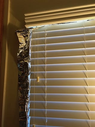 Reflective blanket underneath blinds Image of reflective material peeking out from window blinds