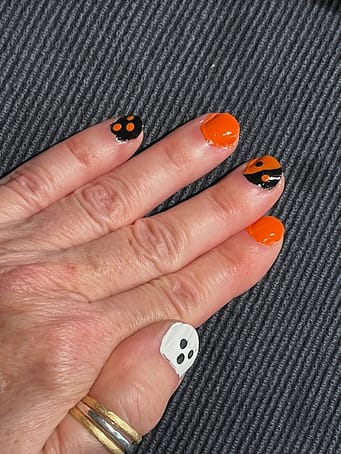 Halloween nails left hand A photo of a right hand with fingernails painted white, orange, or black with an orange design for Halloween