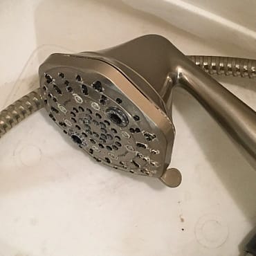 Evil shower head Photo of a dark chrome, hexagonal shower head lying in a plastic tub
