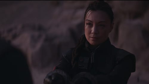 Fennec A woman stares intently off to the left, her hands in thick binders held before her. In the back, unfocused rocks.