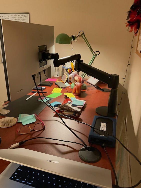 Success - movable monitor Photo of a desk showing the back of a monitor attached to a monitor arm and reading glasses underneath the monitor