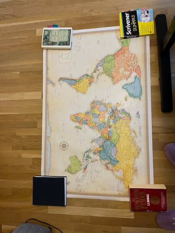Books_on_Map Photo of a world map lying on the floor with heavy books at each corner.