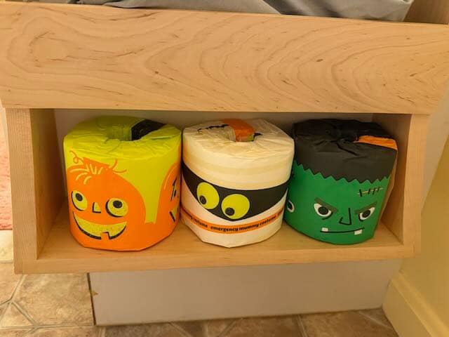 Halloween Toilet Paper Three rolls of Halloween themed toilet paper on a wooden shelf.