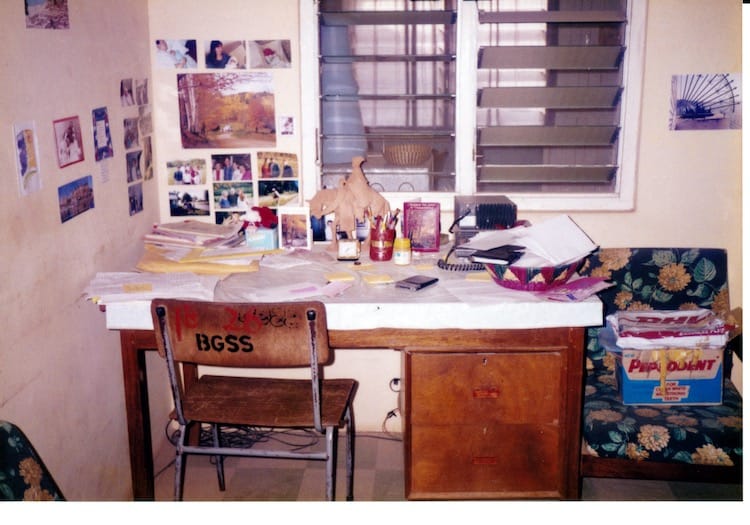 Africa_desk Photo of a wooden desk with two drawers on the right side in front of louvered windows looking into the dining area.