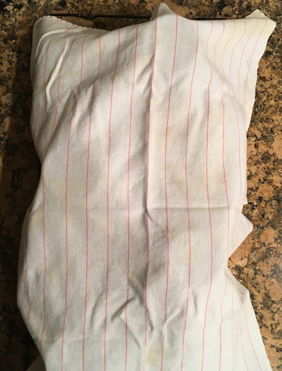Cloth over pumpkin bread Photo of a white dishtowel with thin red stripes draped over loaves of pumpkin bread